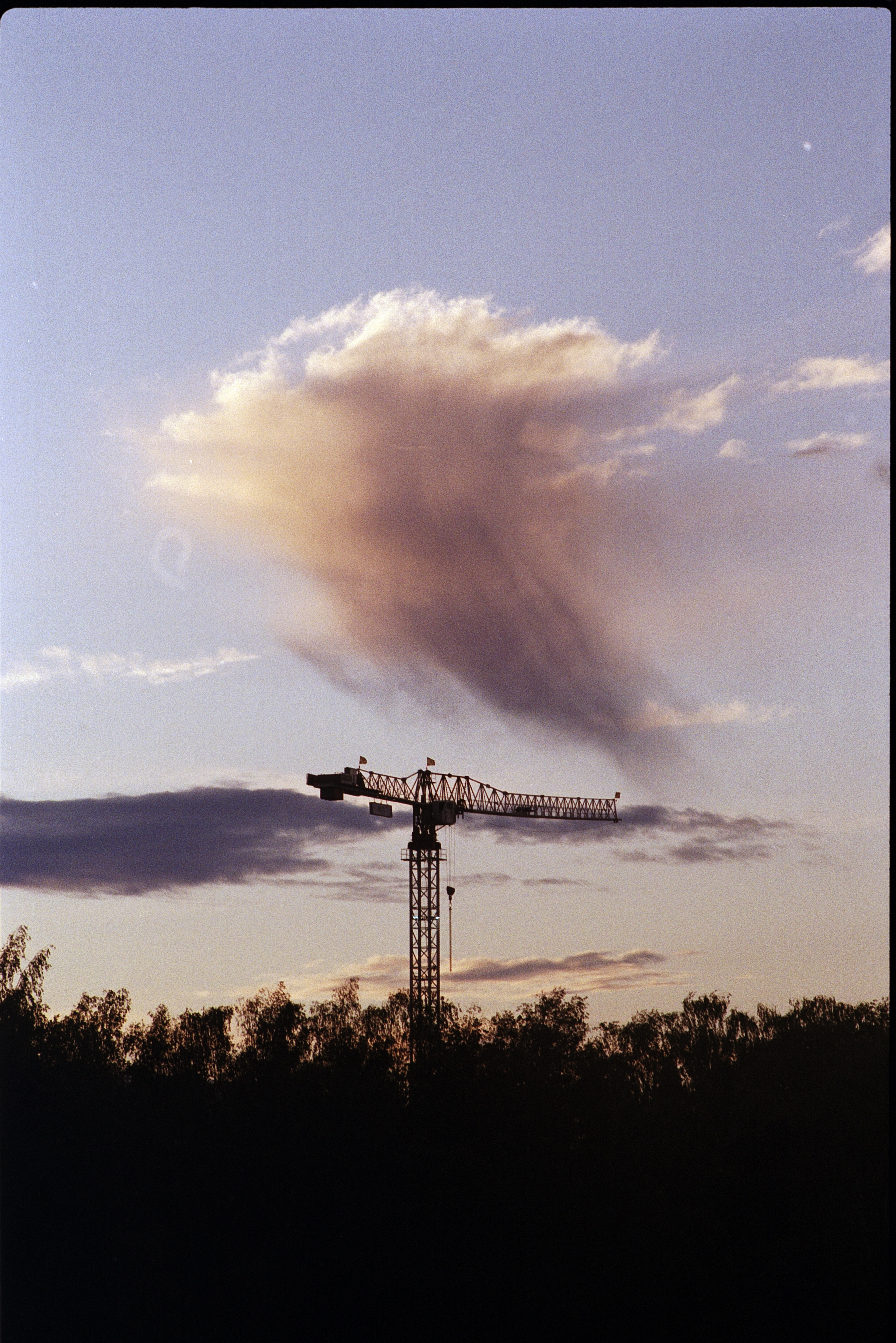 A lonly crane with a lonely cloud obove